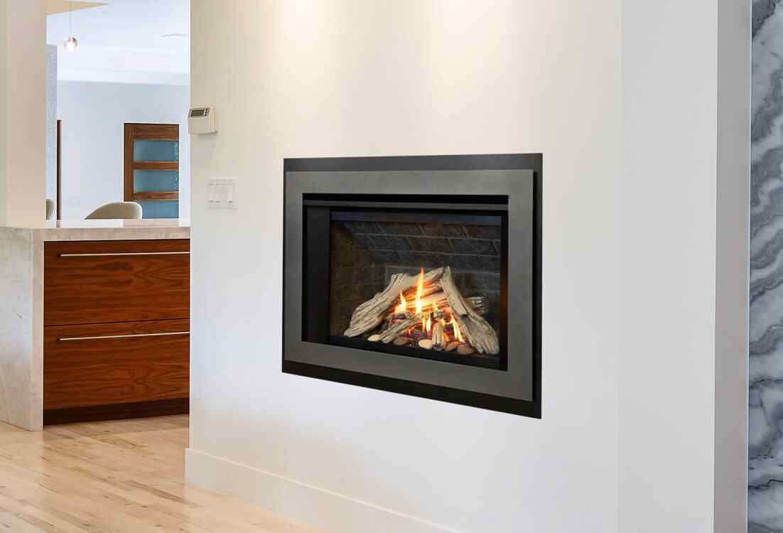 A modern gas fireplace built into a white wall, with visible flames and decorative logs, inside a living area.