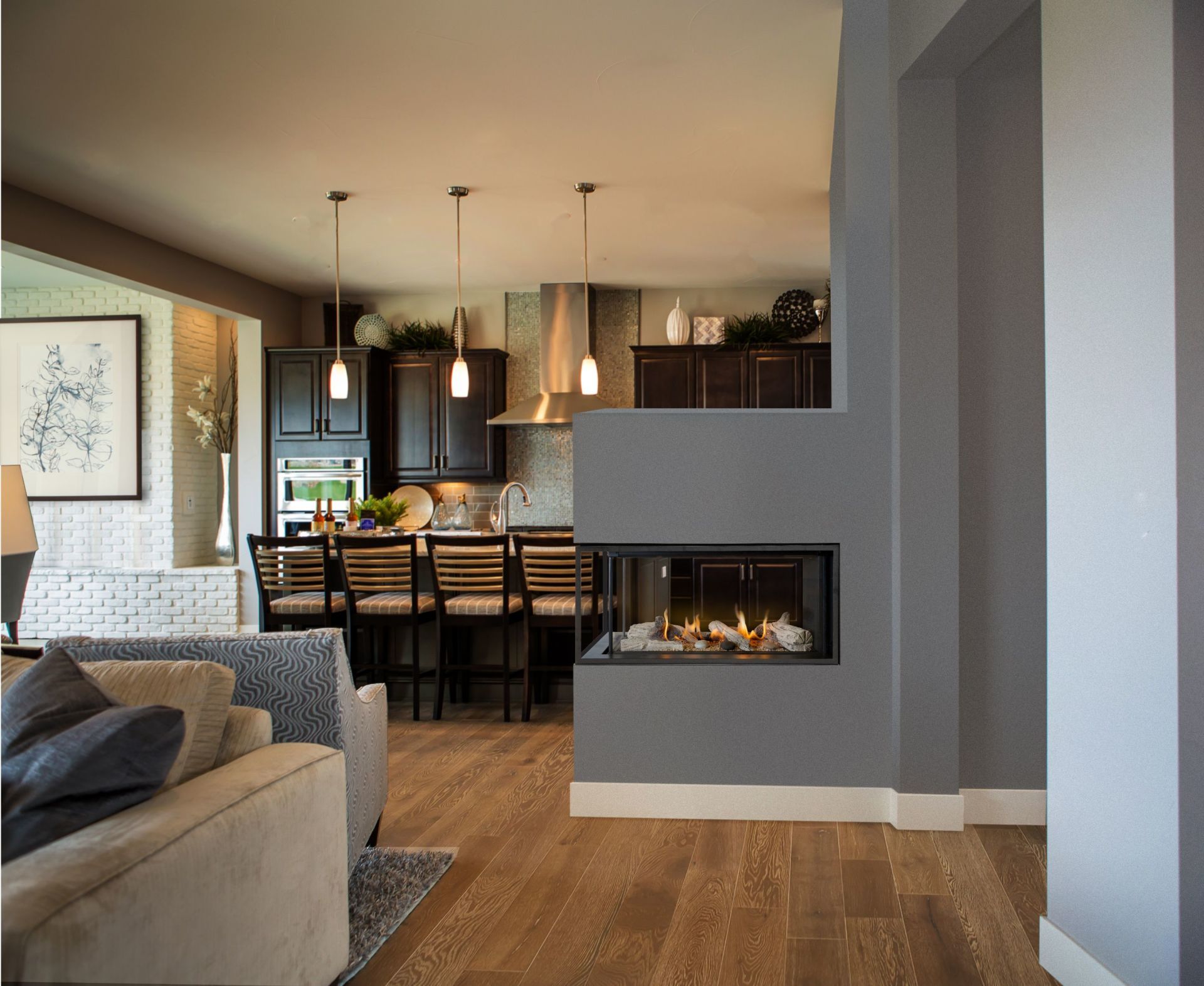 A modern, open-concept living space with a kitchen, fireplace, and seating area. Dark wood cabinets, hardwood floors, and gray walls are featured.