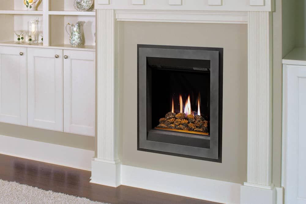 A modern gas fireplace built into a wall with a grey surround and decorative stones, set within a white mantel.