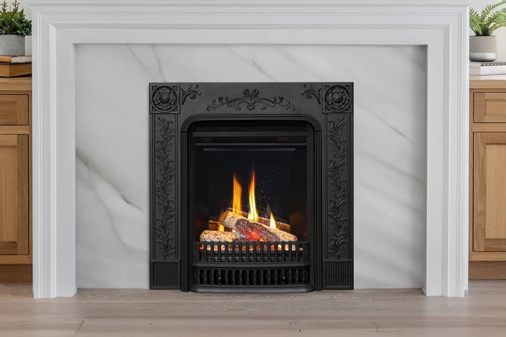 Fireplace with a black firebox and carved detailing, set in a white marble and framed by a white mantel.