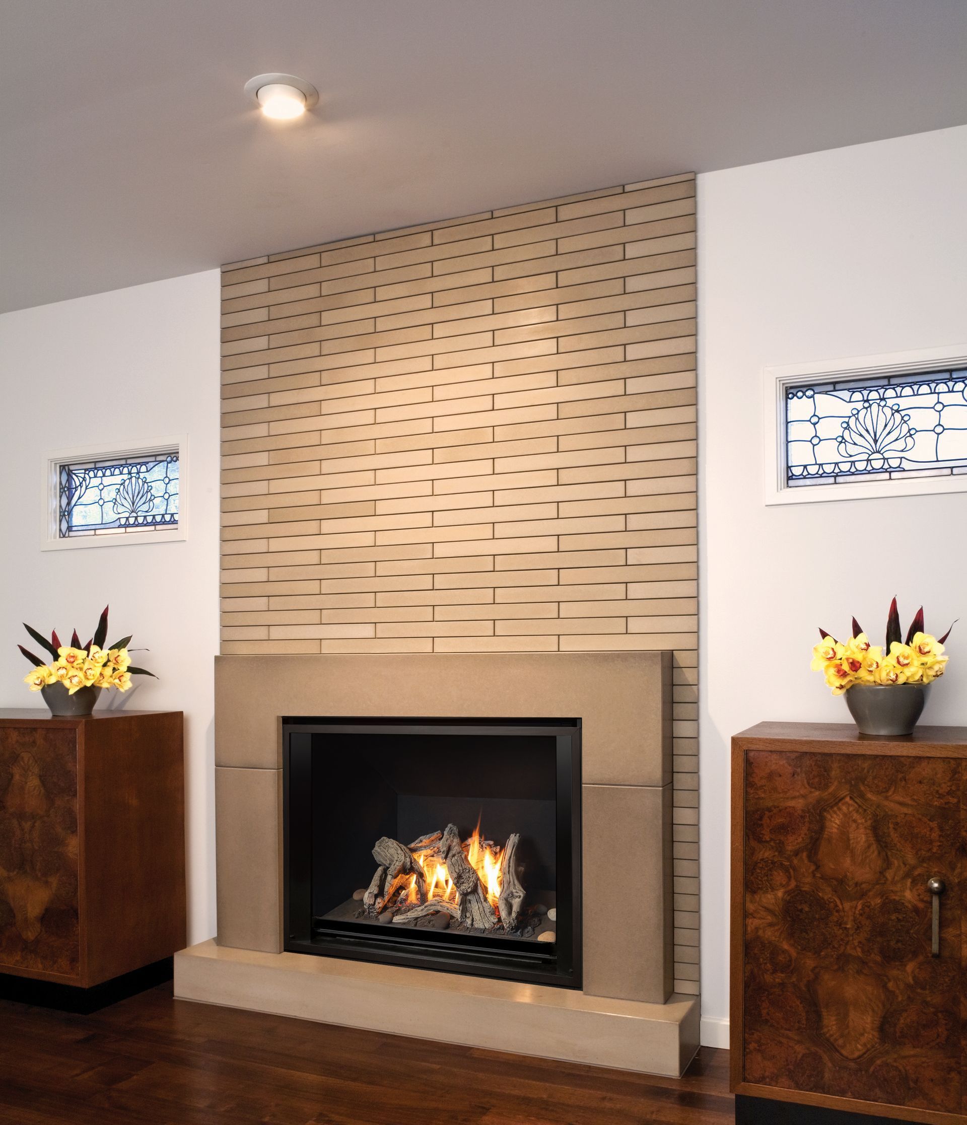 Fireplace with light-colored brickwork, framed by two dark wood cabinets, and illuminated by a spotlight.