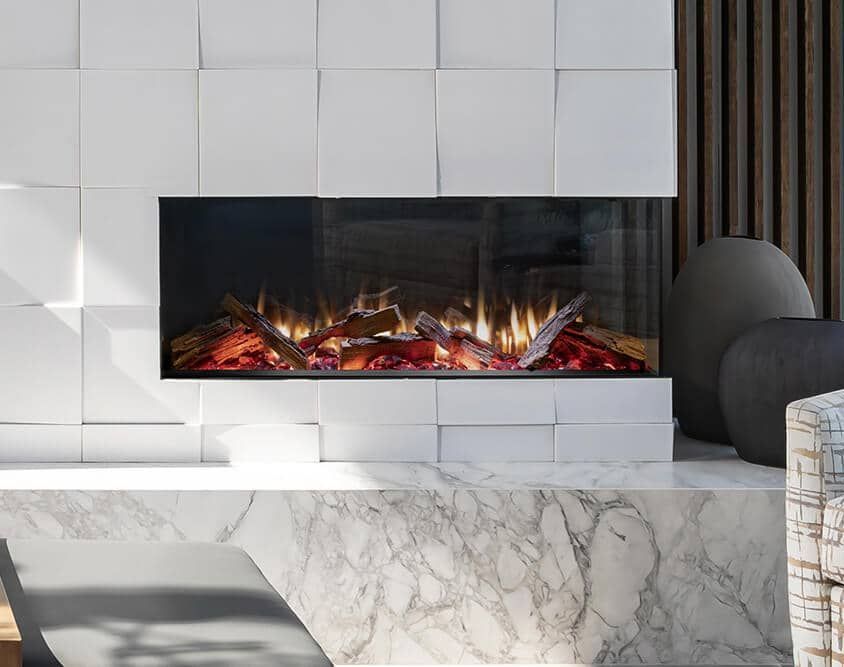 Modern electric fireplace with faux logs and flames set within a marble and white tiled wall.