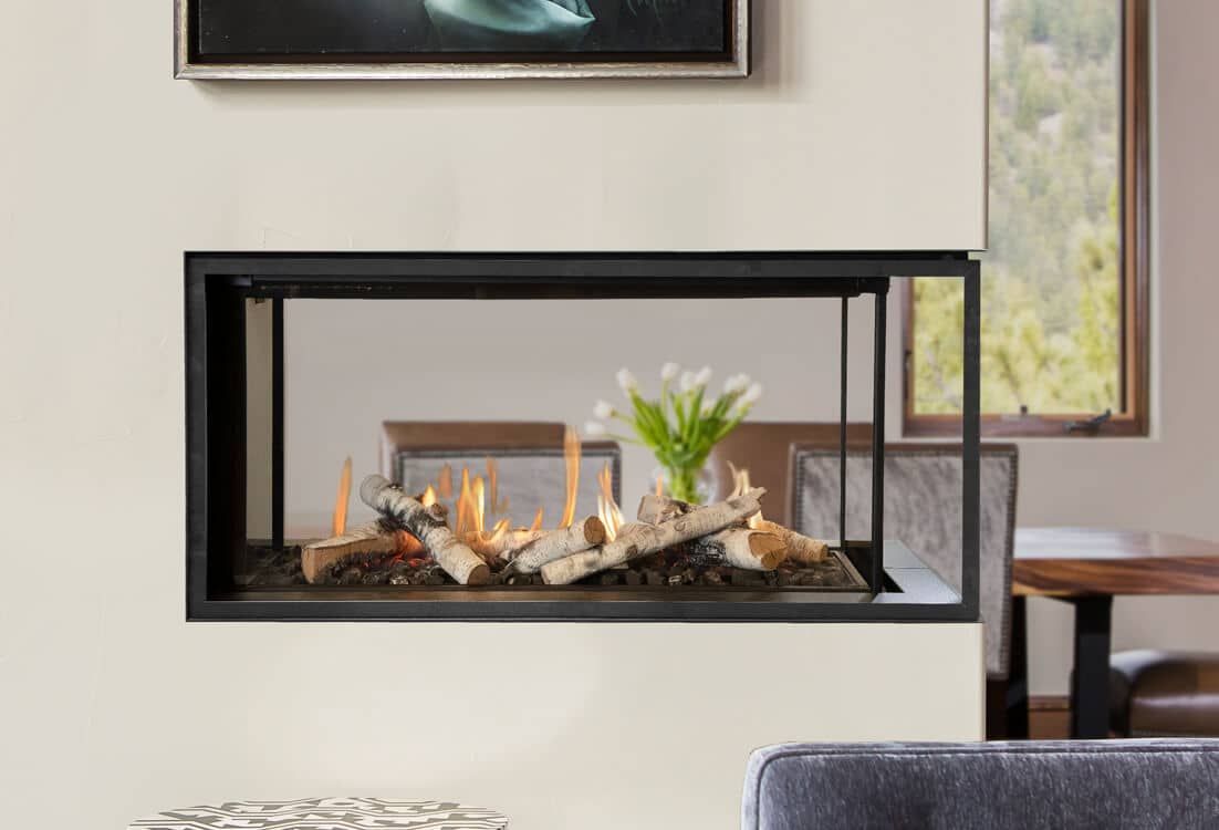 Modern, black-framed fireplace with simulated logs and flames set into a beige wall. A window and decor are visible in the background.