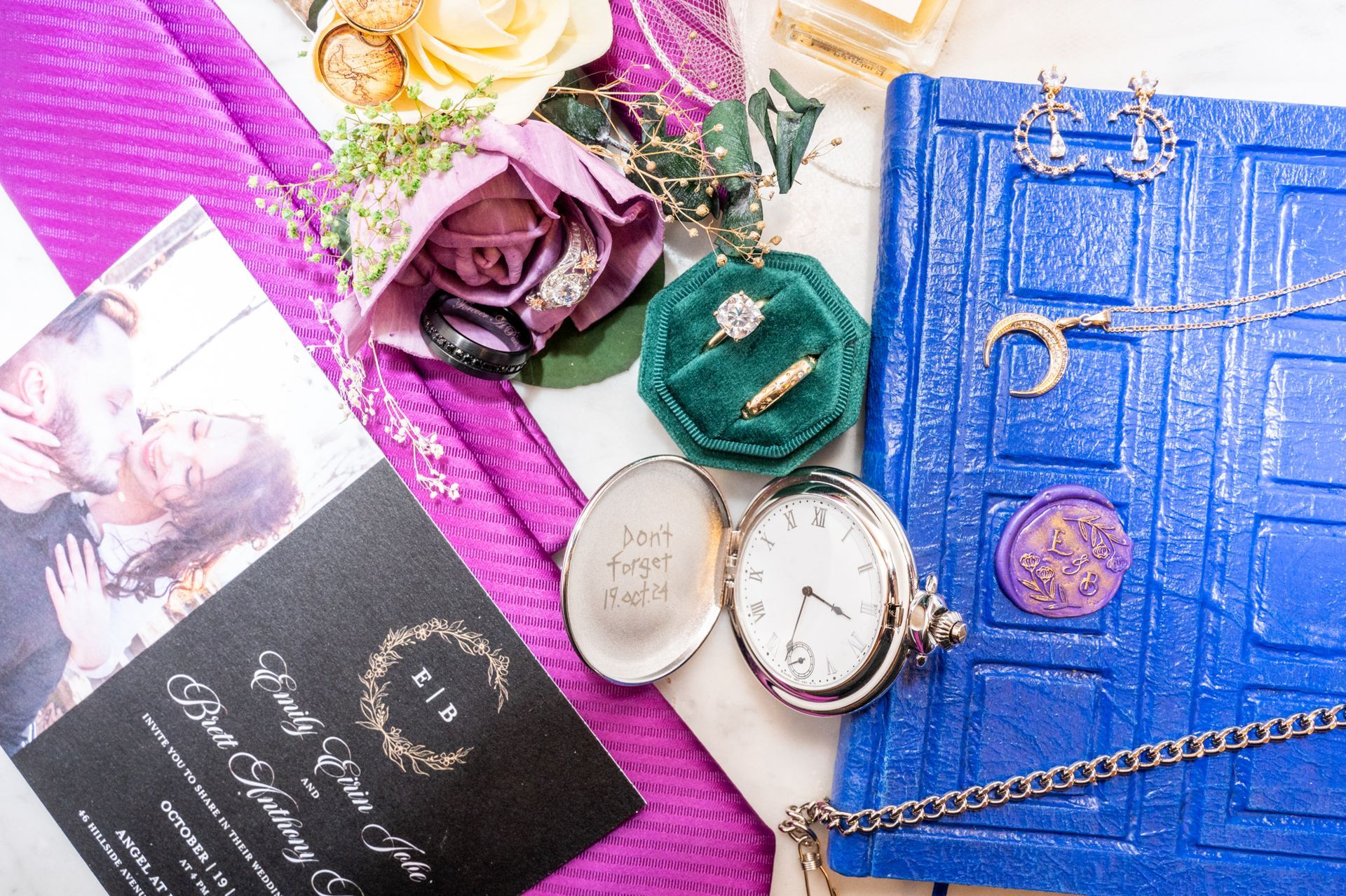 Wedding details: Rings, flowers, watch, jewelry, invitation, blue book, purple accents.