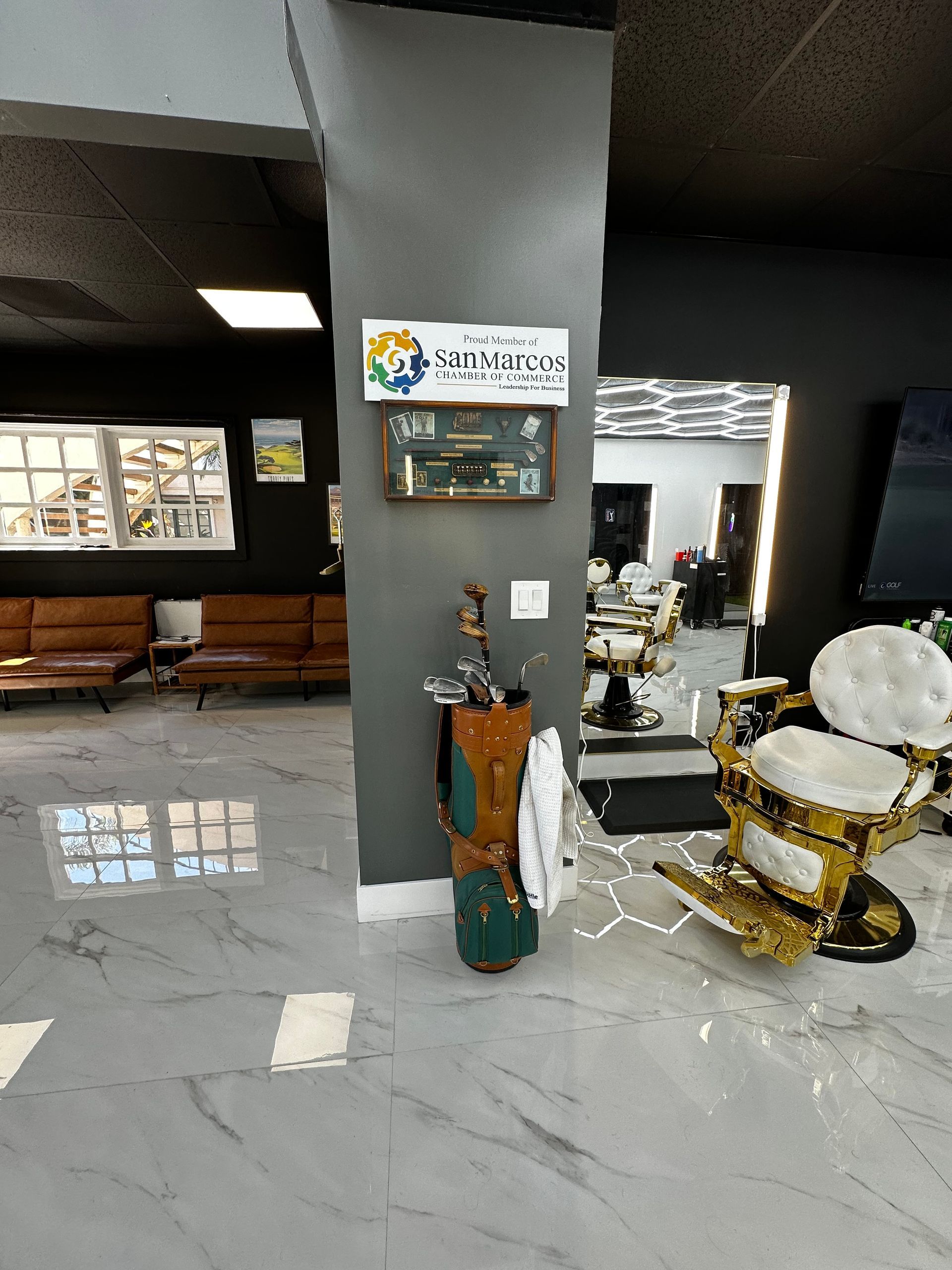 Lobby with a gray pillar, wall sign, benches, and a decorative gold-and-white statue on a tiled floor