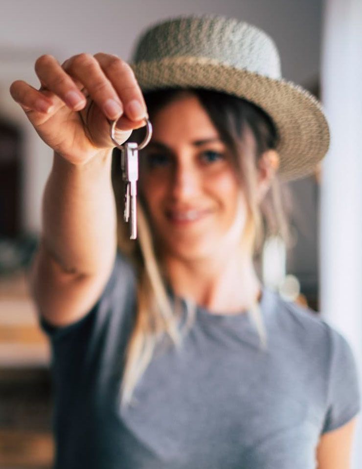 Une femme portant un chapeau tient un trousseau de clés.