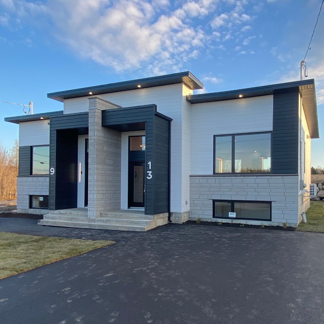 Une maison blanche et noire avec un ciel bleu en arrière-plan