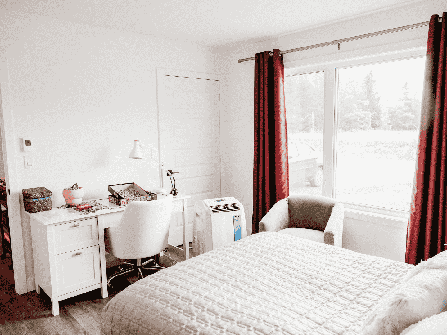 Une chambre avec un lit, un bureau, une chaise et une fenêtre.
