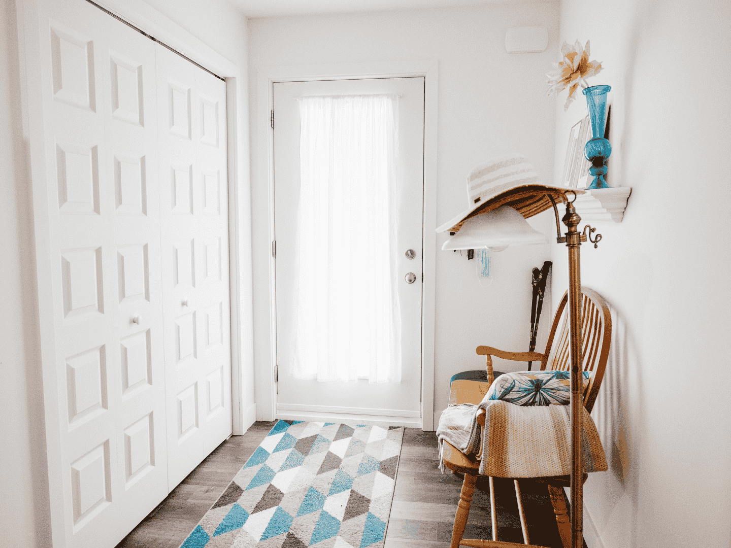 Un couloir avec une chaise et un tapis devant une porte.