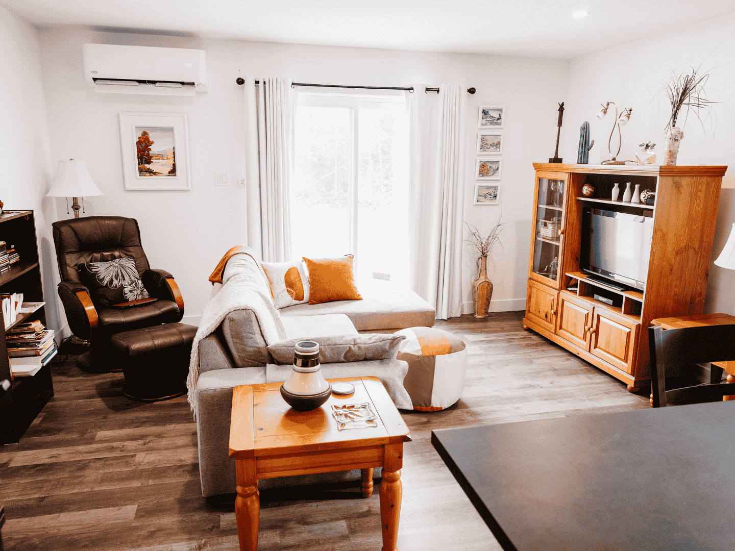 Un salon avec un canapé, une chaise, une table et une télévision.