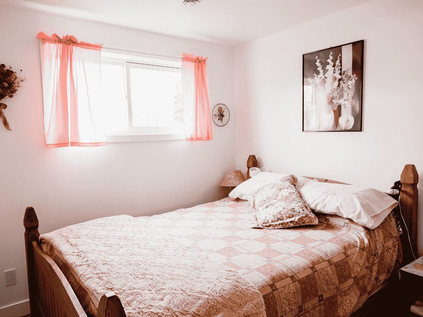 Une chambre avec un lit et une fenêtre avec des rideaux roses.
