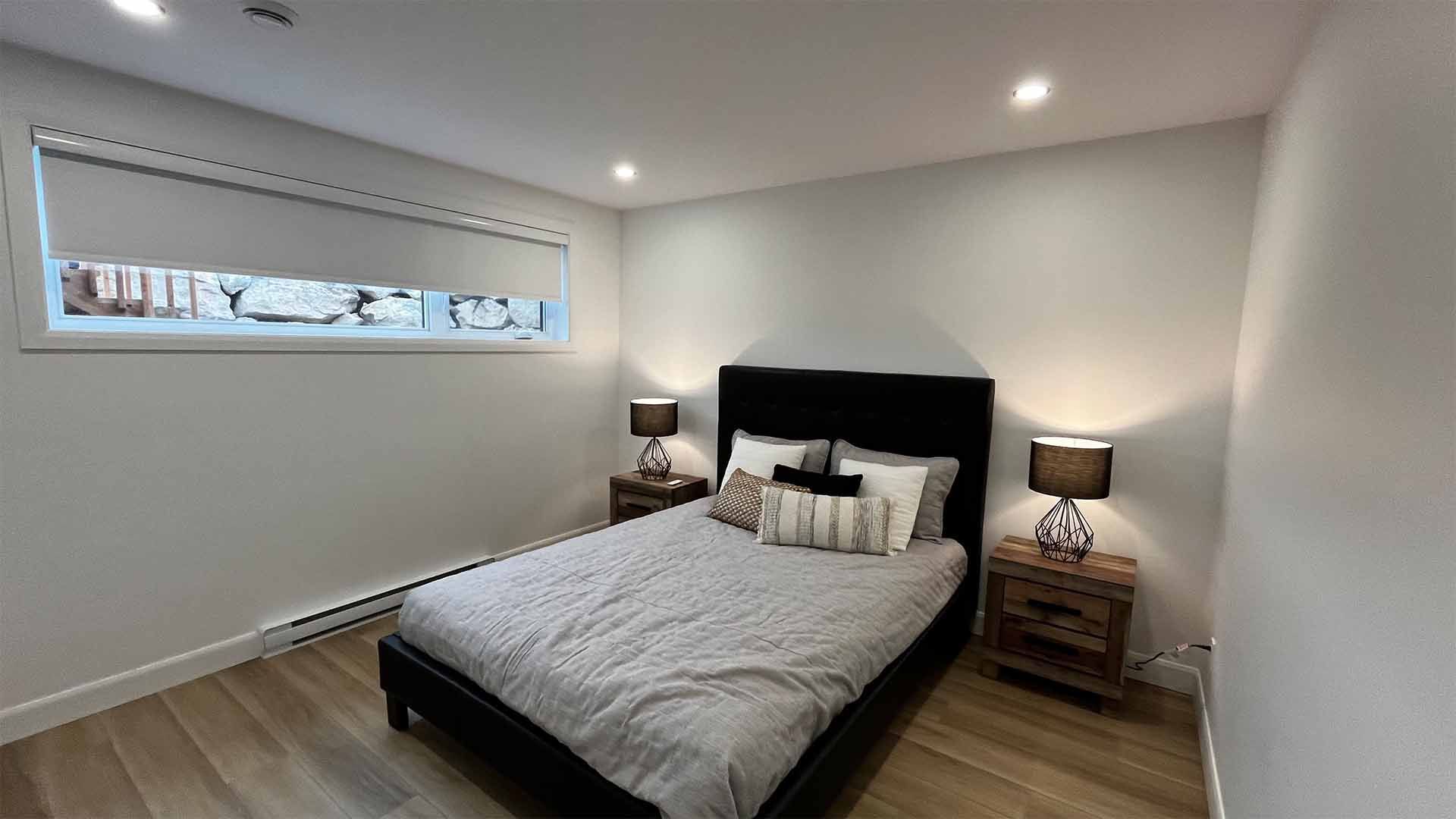 Une chambre avec un lit, des tables de nuit, des lampes et une fenêtre.
