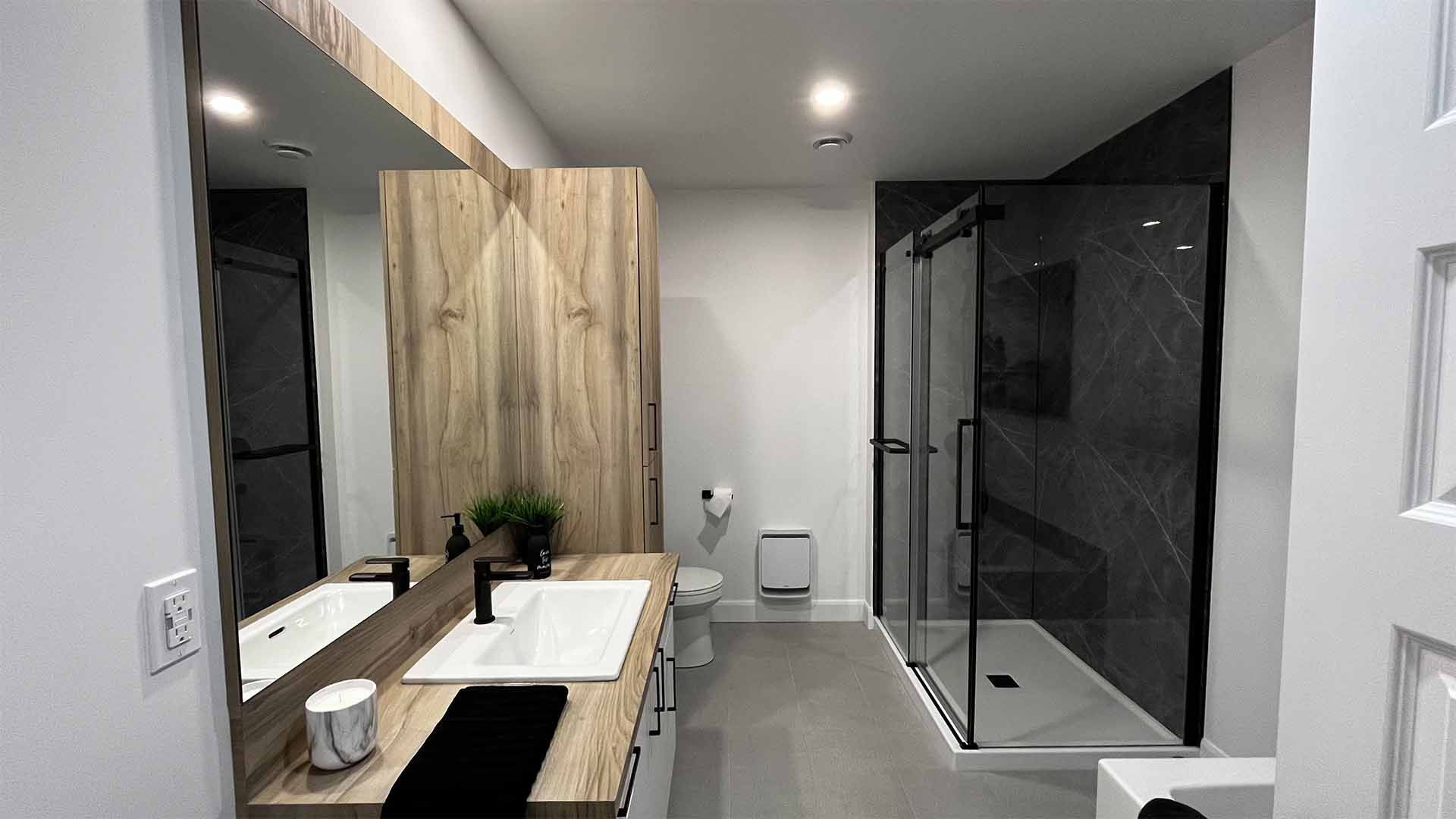 Une salle de bain avec deux lavabos, un WC et une douche à l'italienne.
