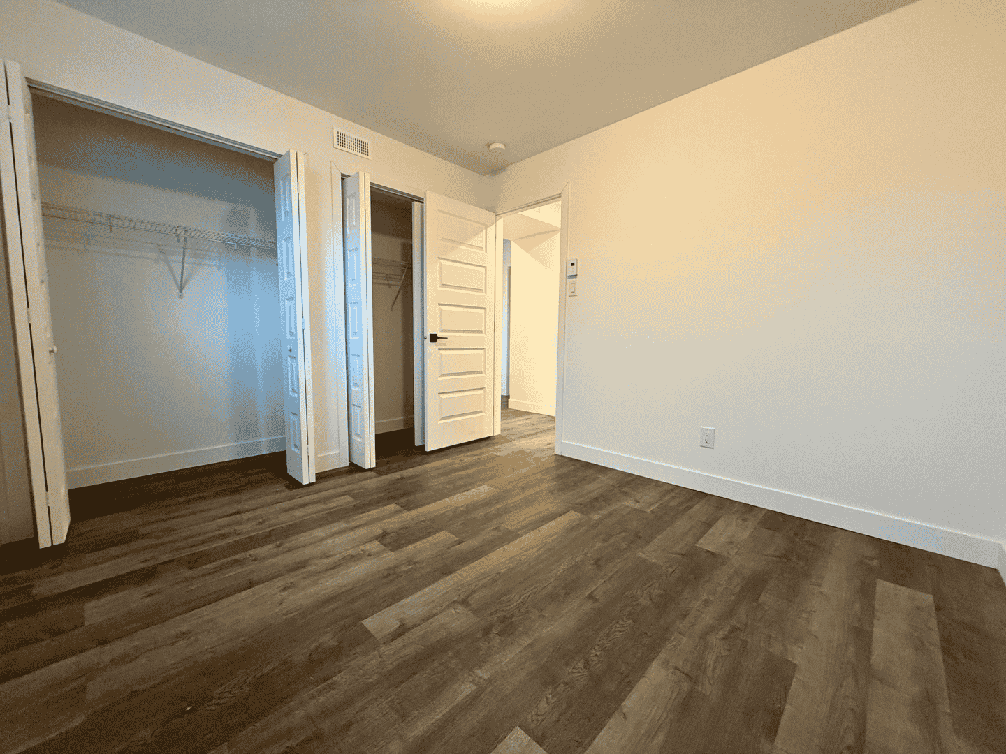Une chambre vide avec parquet et un placard.