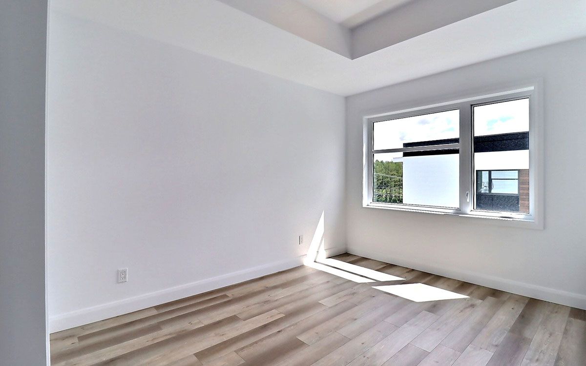 Une pièce vide avec du parquet et deux fenêtres.