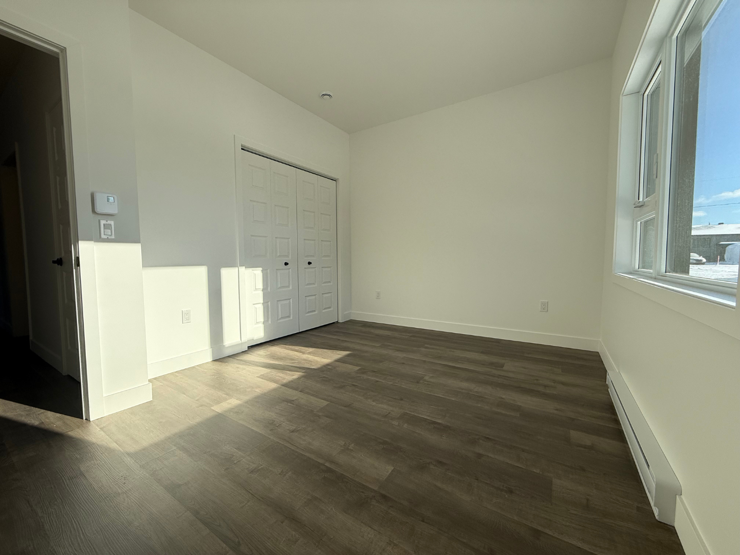 Une pièce vide avec du parquet et une fenêtre.