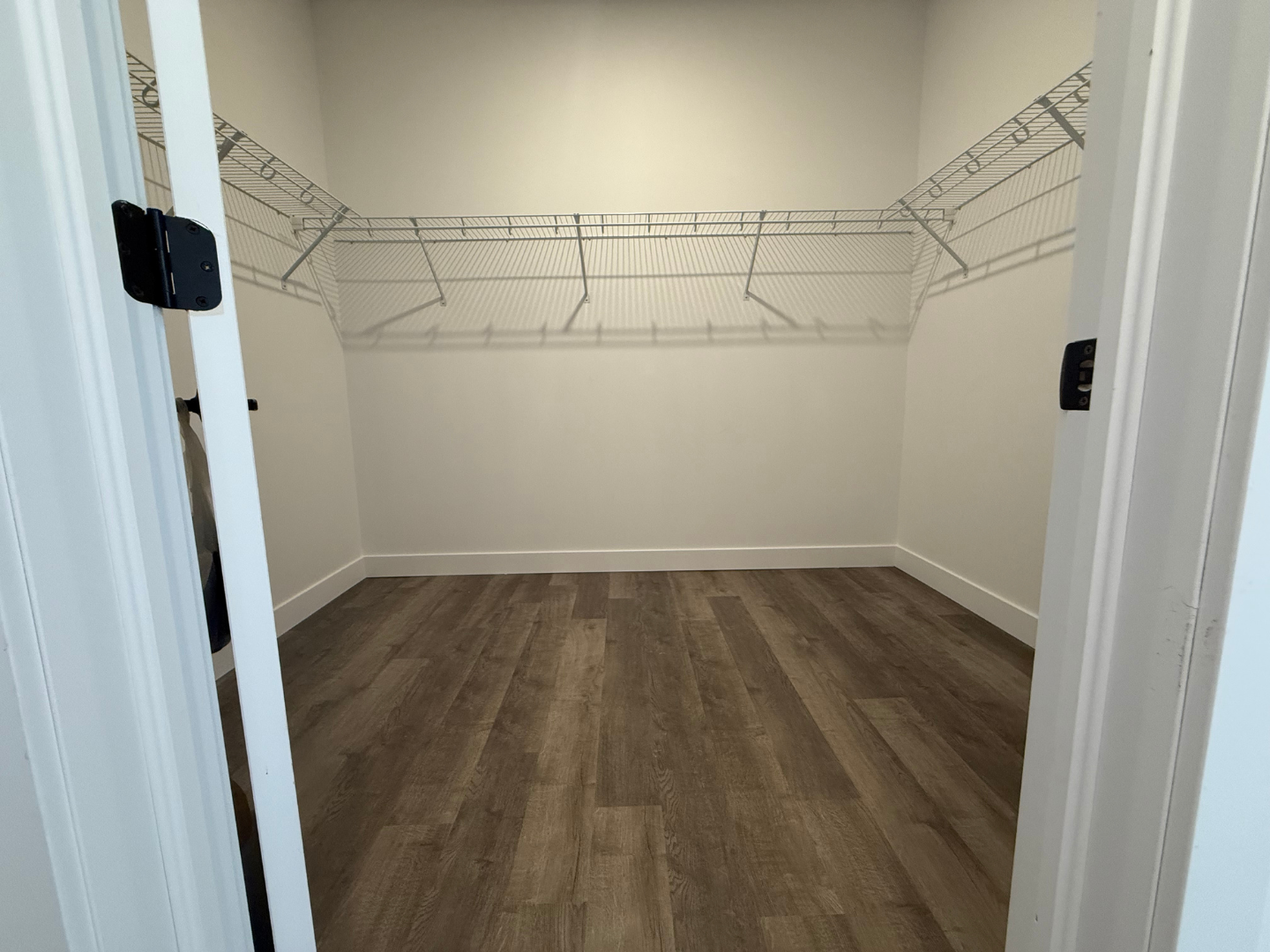 Un dressing vide avec parquet et étagères grillagées.