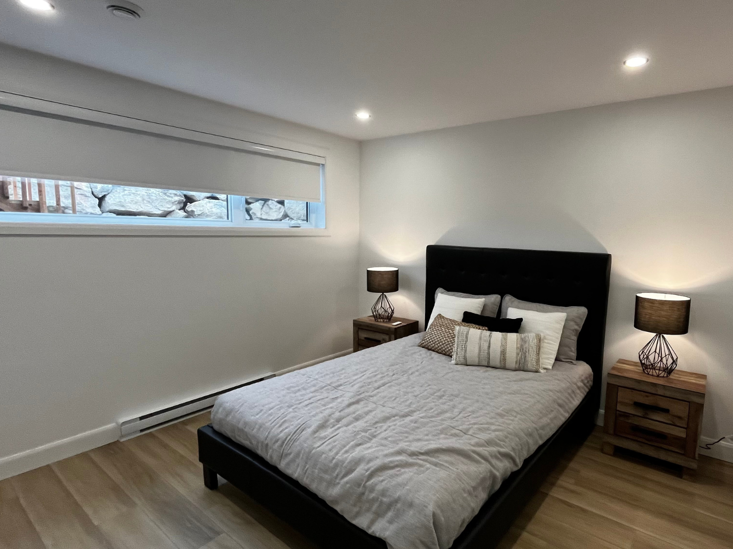 Une chambre avec un lit, des tables de nuit, des lampes et une fenêtre.