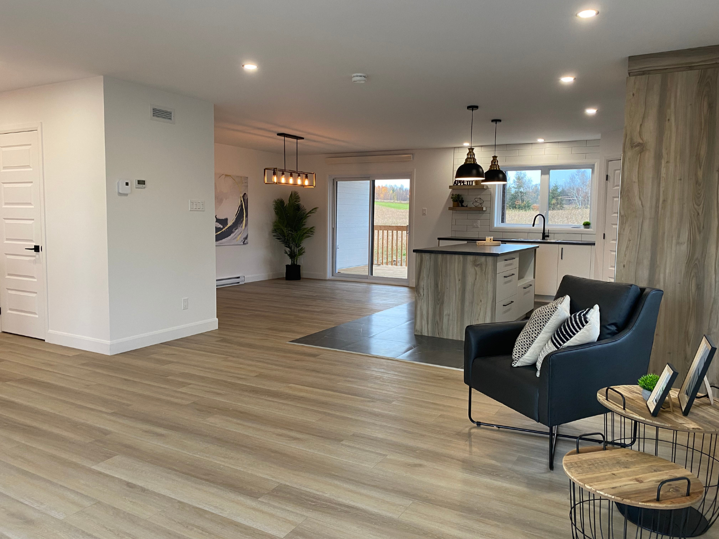 Un salon avec parquet, une chaise et une table.