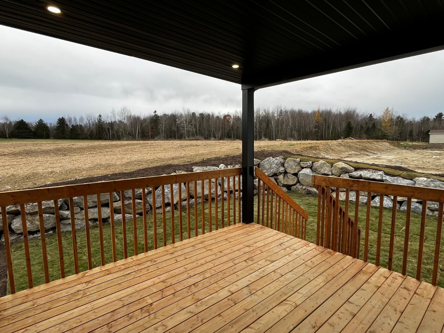 Une terrasse en bois avec une balustrade et une vue sur un champ.