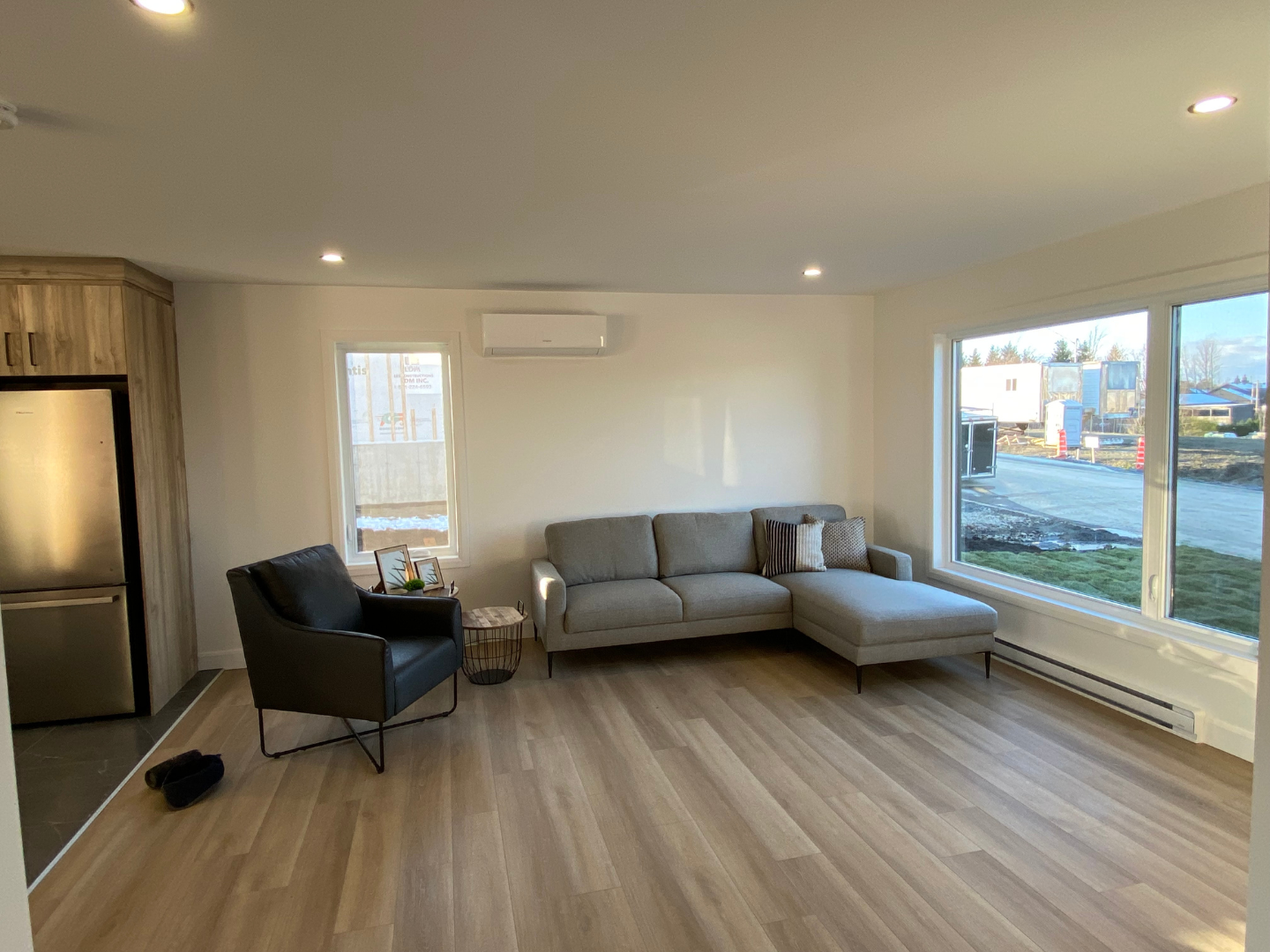 Un salon avec un canapé, une chaise et de grandes fenêtres.