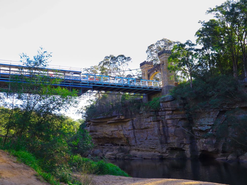 A Bridge Over A River Surrounded By Trees And Rocks — Ridgeline Building Co In Berry, NSW

