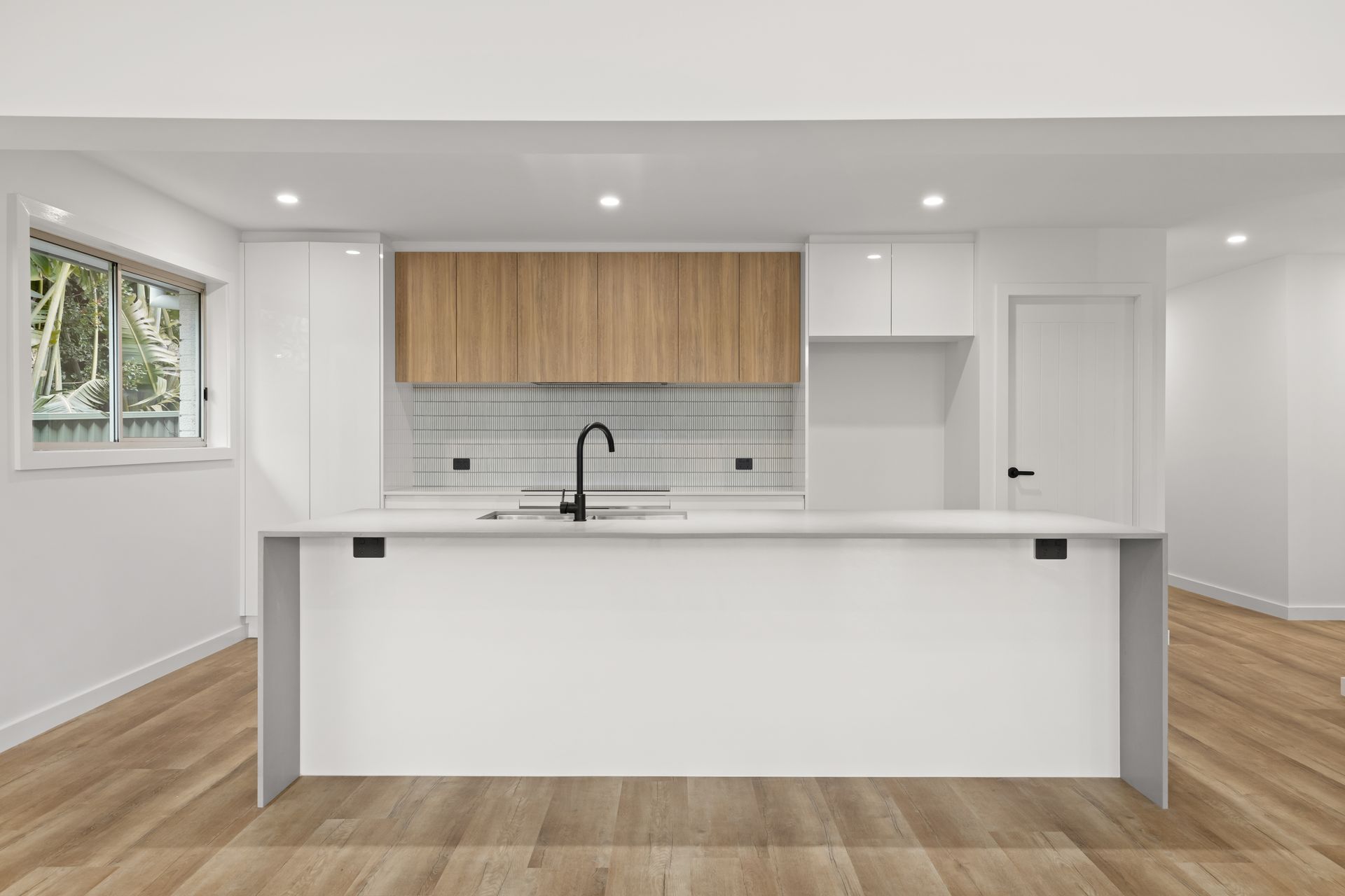 Modern kitchen with white cabinets, wooden upper cabinets, and a white island.
