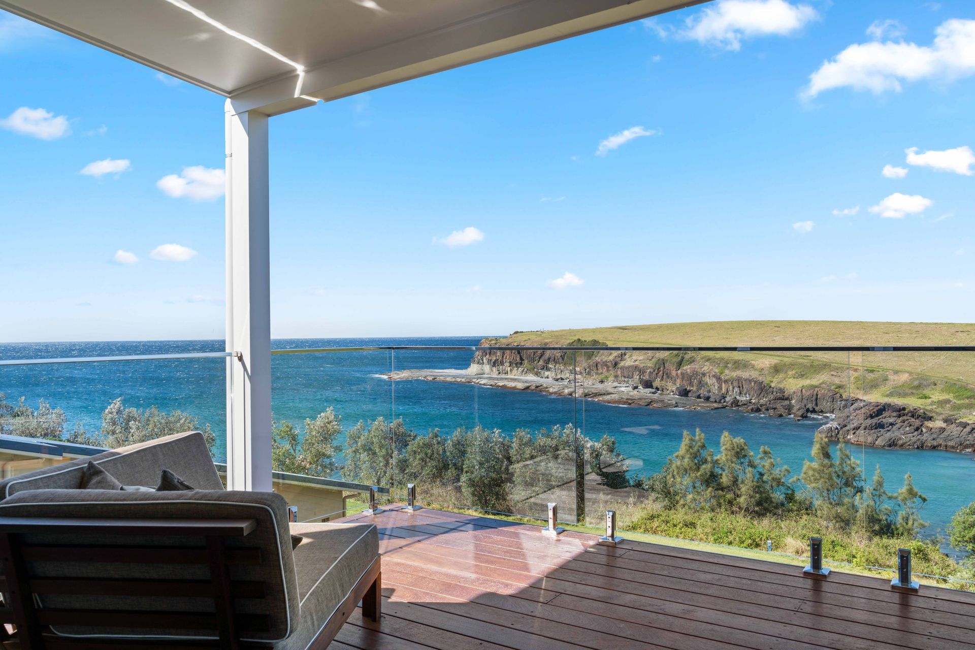 Deck with a lounge chair overlooking a blue ocean, under a clear sky.