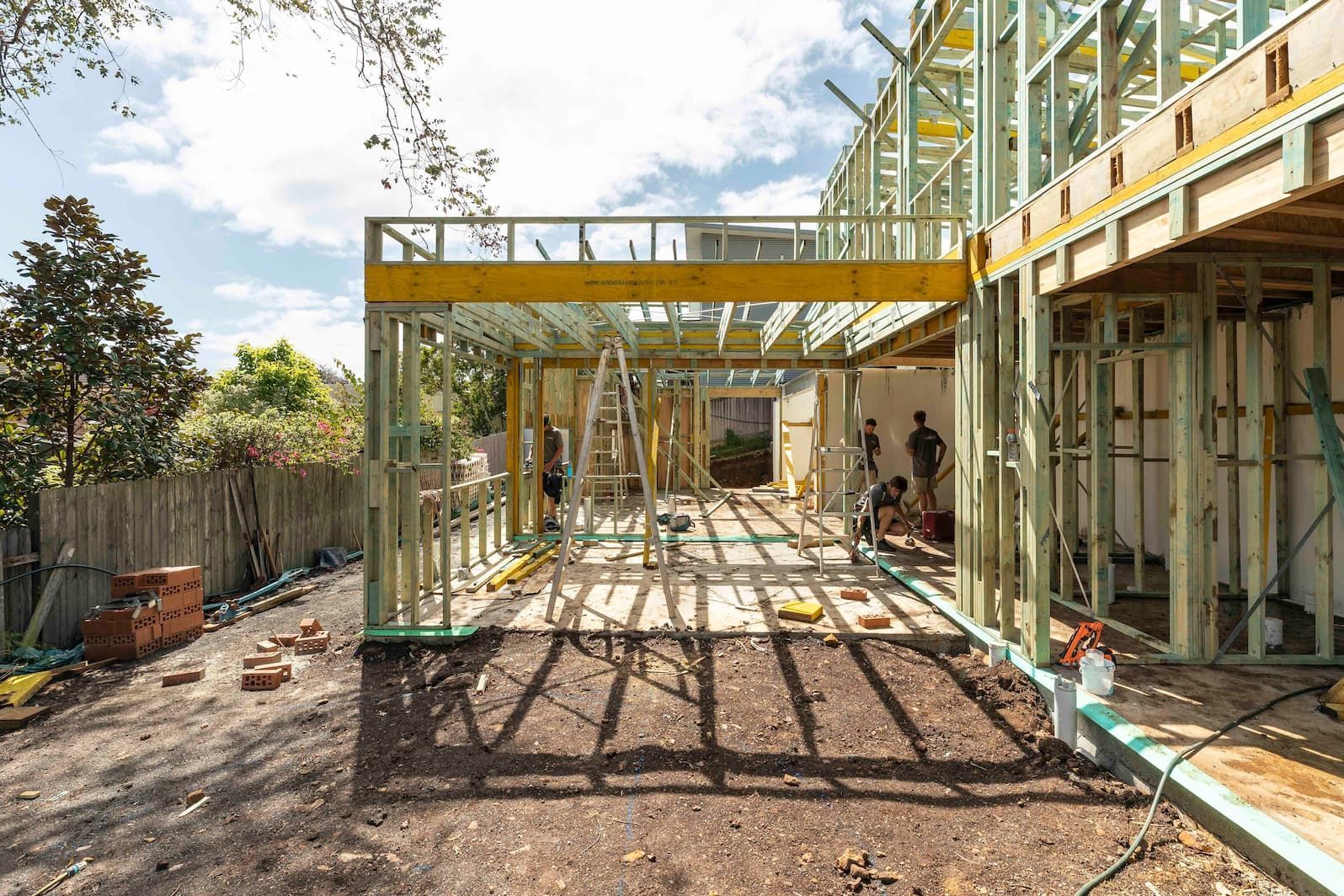 Construction site: Wooden frame of a house in progress with workers, sunny day.