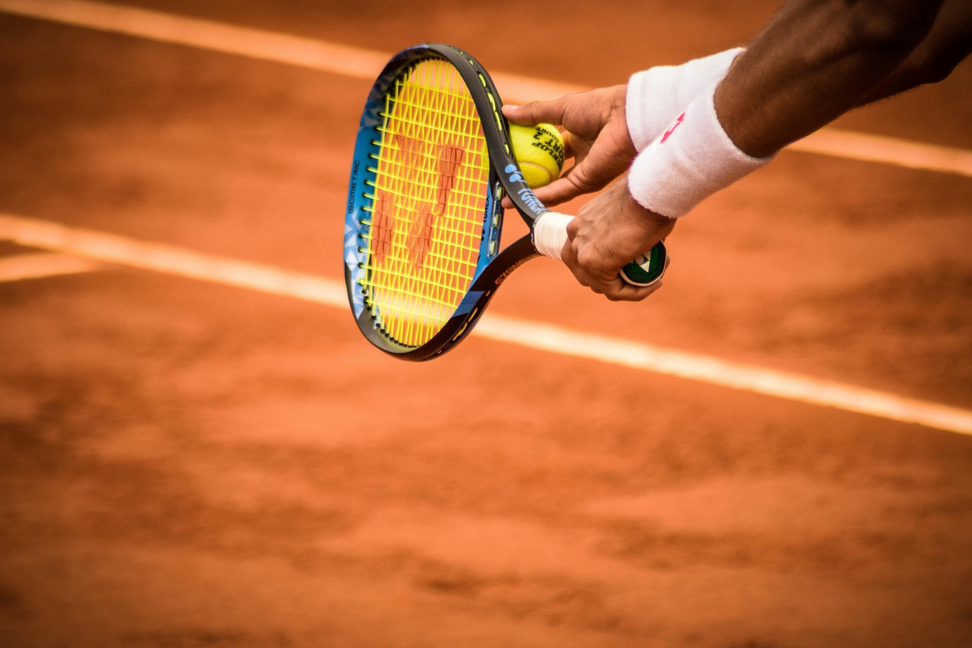 A person is holding a tennis racquet and a tennis ball on a tennis court.