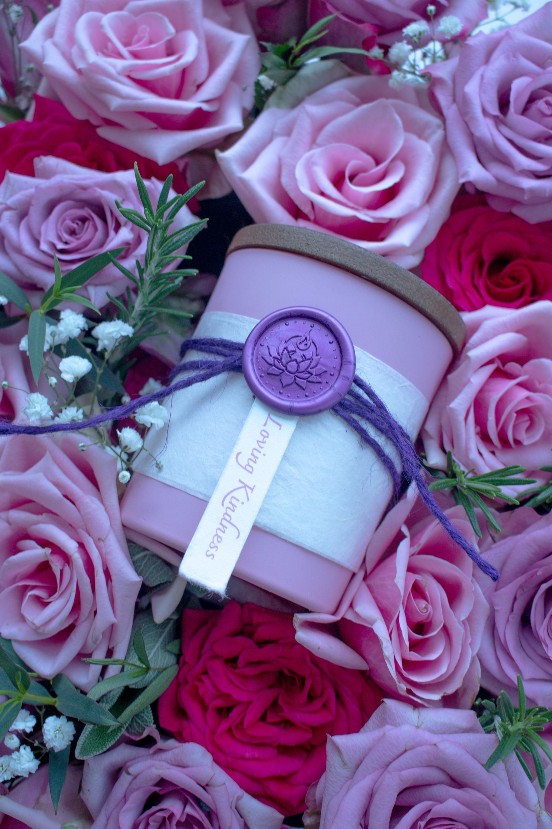 Loving Kindness candle by Eldara nestled in a bed of pink roses. Infused with rose quartz and sacred oils to nurture love, tenderness and emotional healing.
