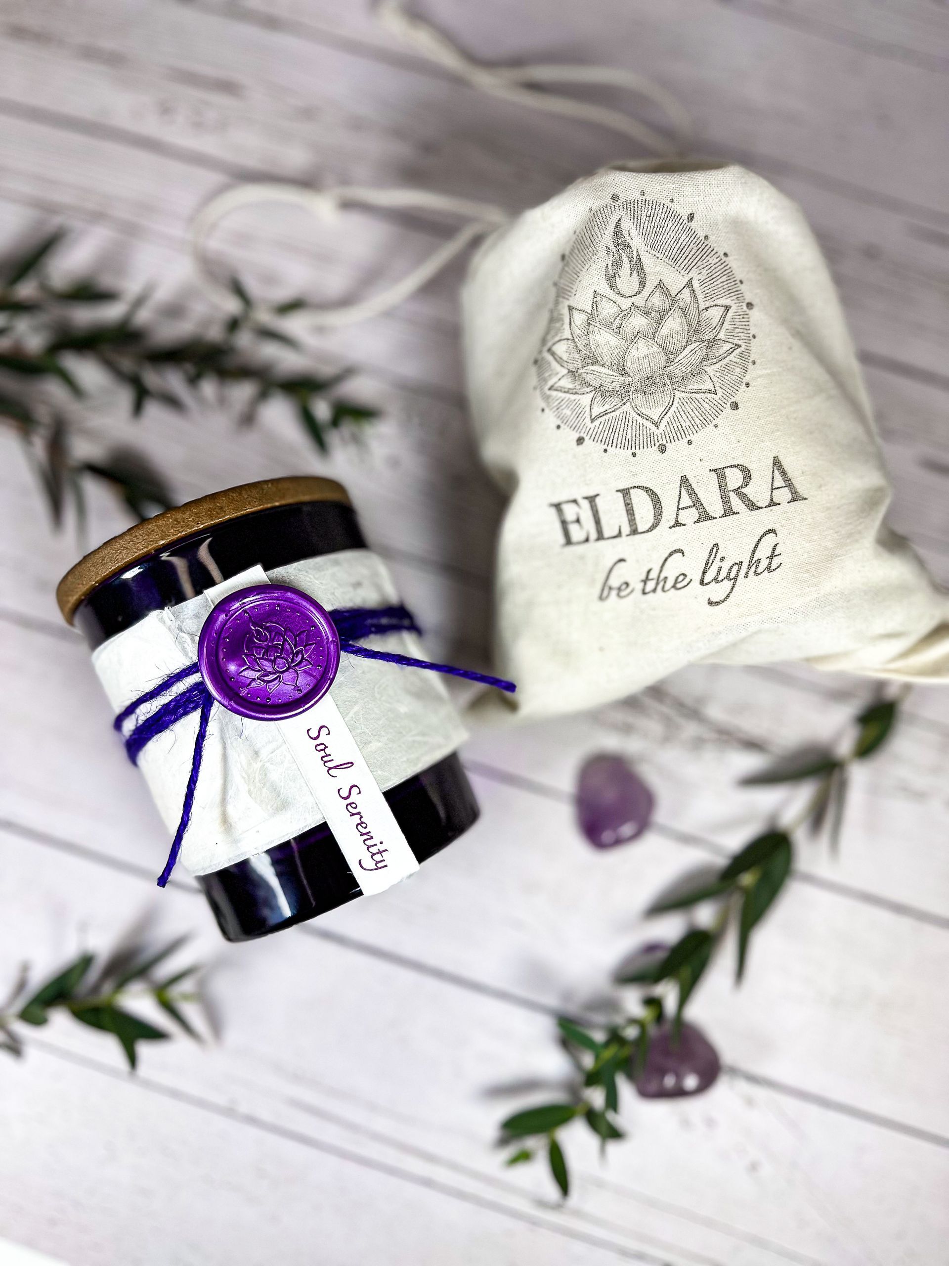 Soul Serenity candle by Eldara alongside its cotton canvas bag. A ritual candle infused with amethyst and sacred oils for calm, clarity and inner peace.