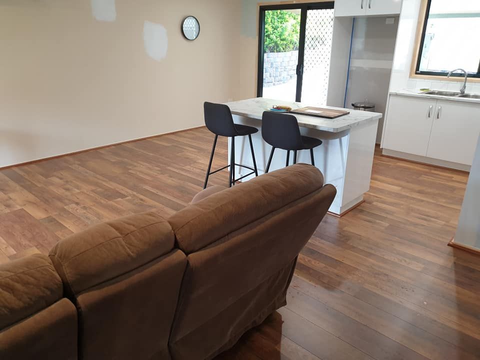 A Living Room With a Couch, Bar Stools, and a Kitchen — Bob Ryan's Home Improvements & Construction Pty Ltd in Beecher, QLD