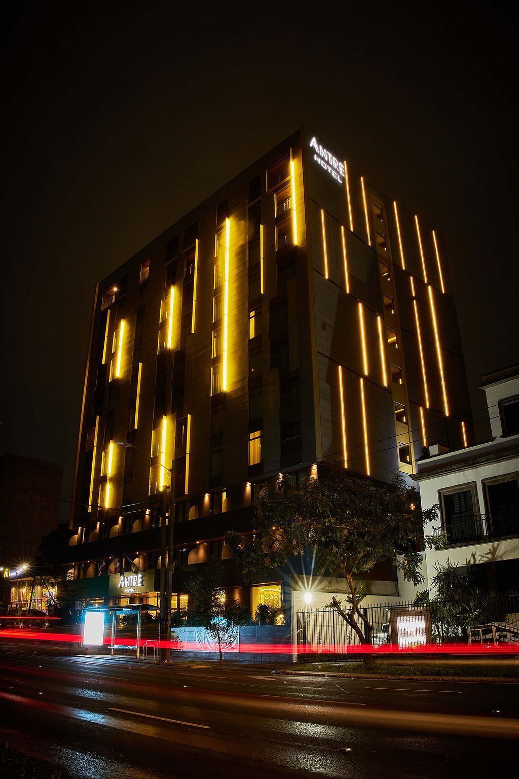 Paisaje urbano nocturno con un rascacielos amarillo brillantemente iluminado y tráfico en la calle de abajo.