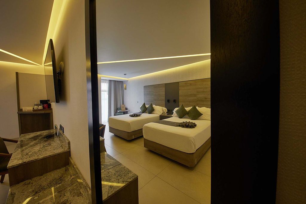 Elegante habitación de hotel con dos camas, luces de guirnalda cálidas y una mesita de noche en un interior acogedor.