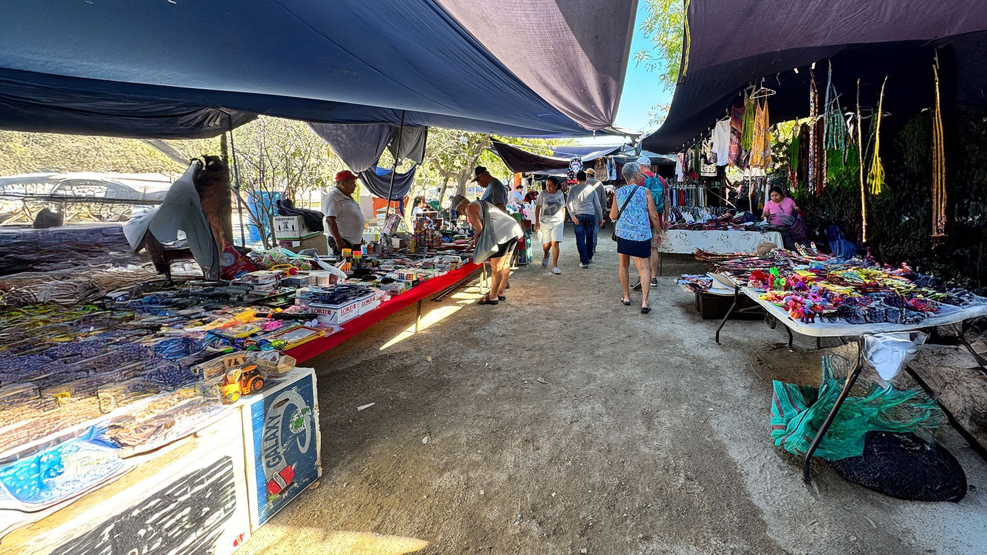 A crowd of people are walking down a busy street at a market.