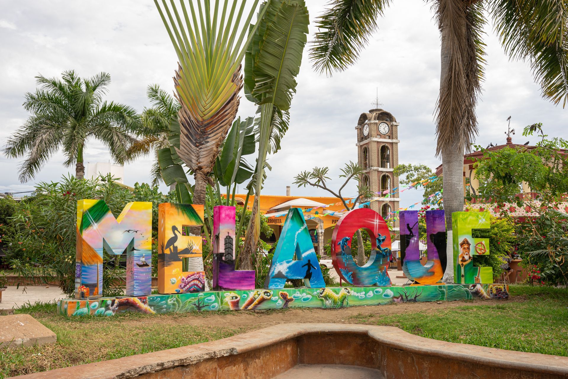 A colorful sign in a park with palm trees in the background.