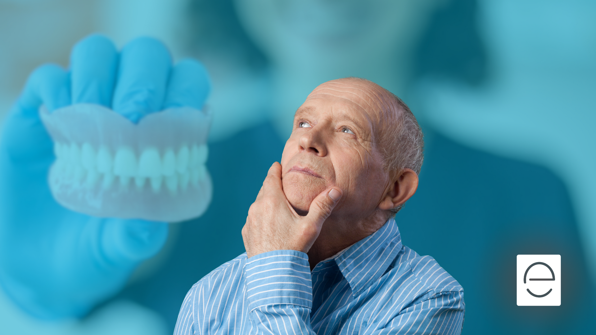 A man is holding a denture in his hand and looking up at it.