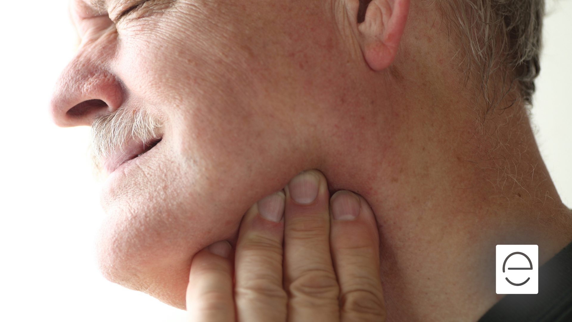 A man with a mustache is holding his mouth in pain.