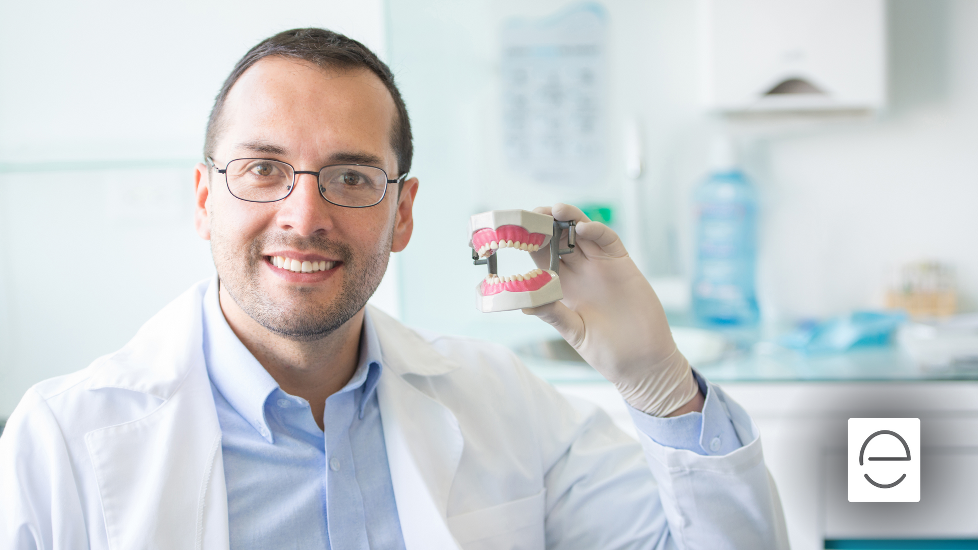 A dentist is holding a model of teeth in his hand.