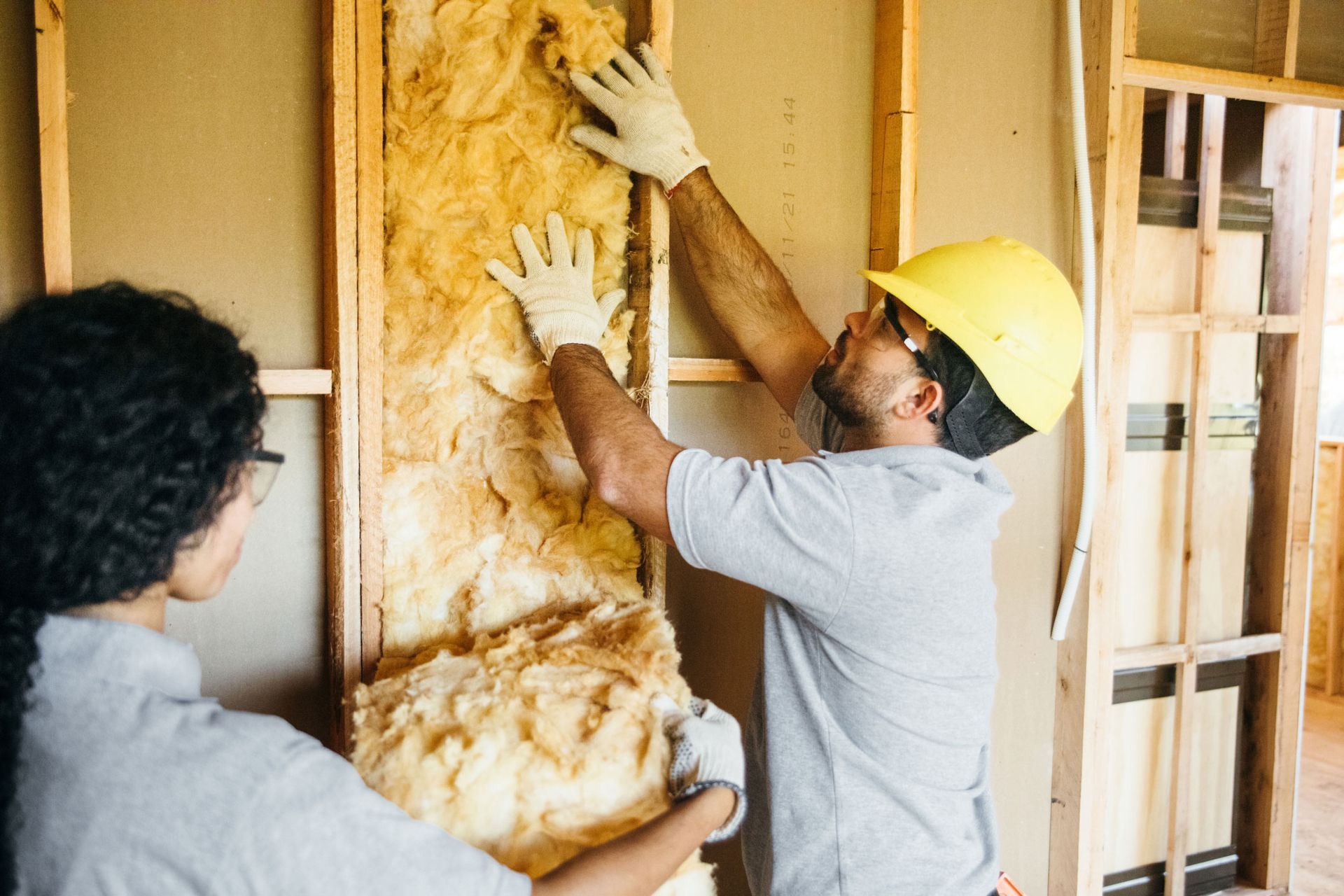 Construction workers are fitting insulation in the frame, showcasing insulation services. Construction workers are fitting insulation in the frame, showcasing insulation services.