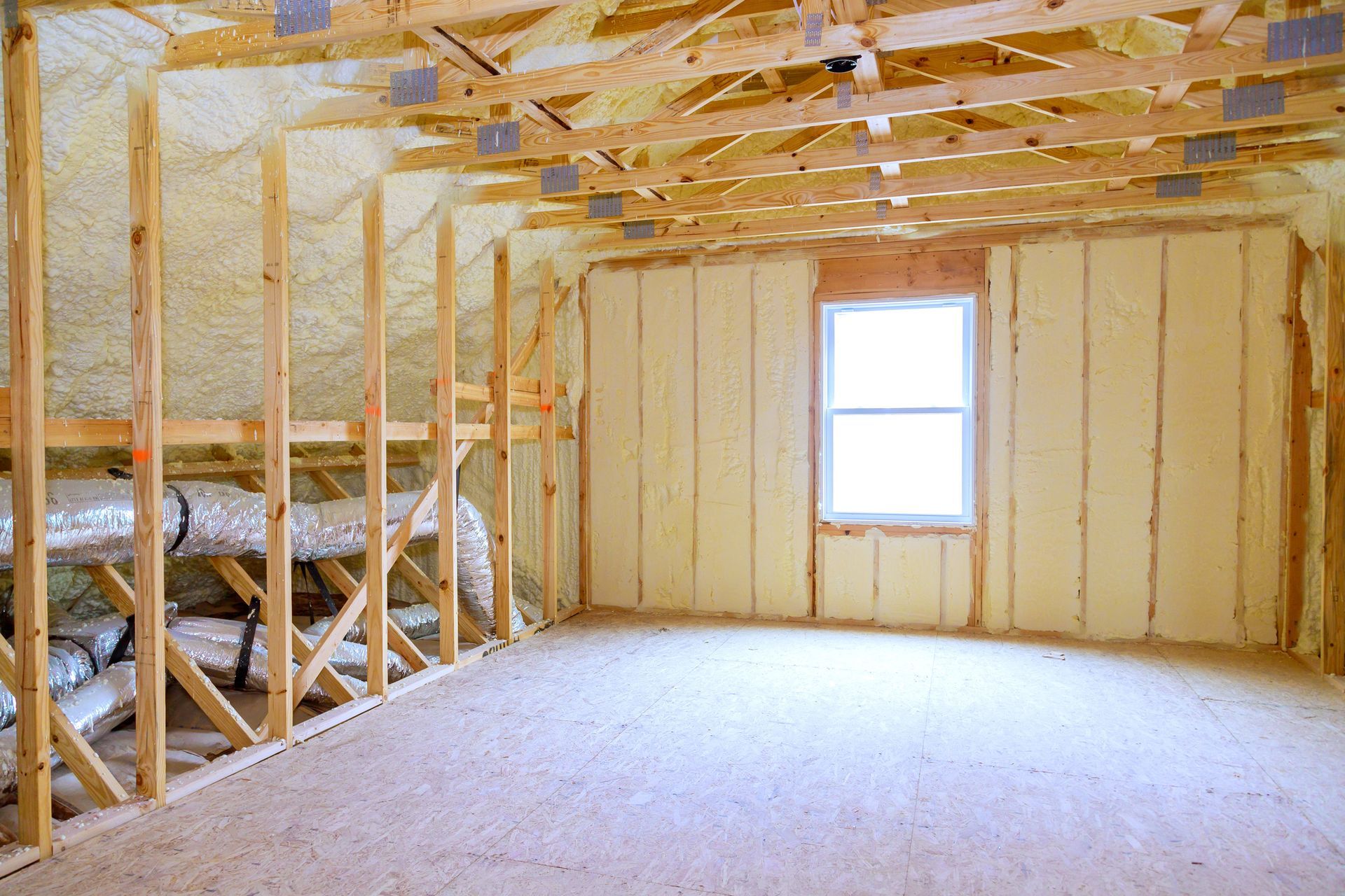 An empty room with wooden beams and insulation on the walls.
