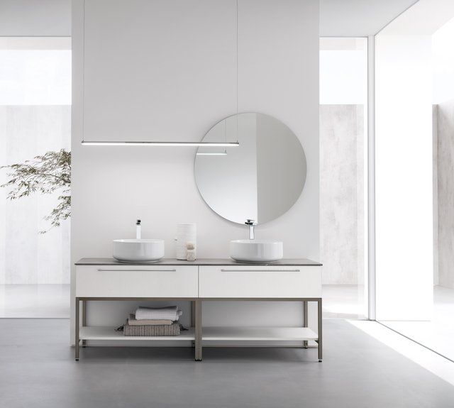 Un bagno con due lavandini e uno specchio rotondo