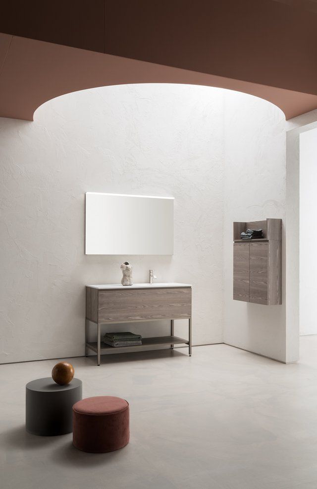 Un bagno con lavandino, specchio e pouf