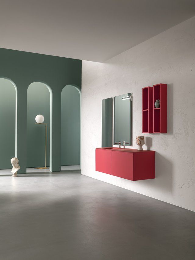 Un bagno con un mobiletto rosso e due specchi.