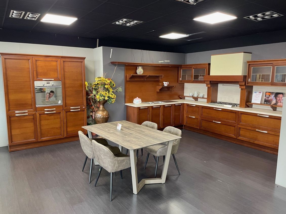 Una cucina con mobili in legno, tavolo e sedie
