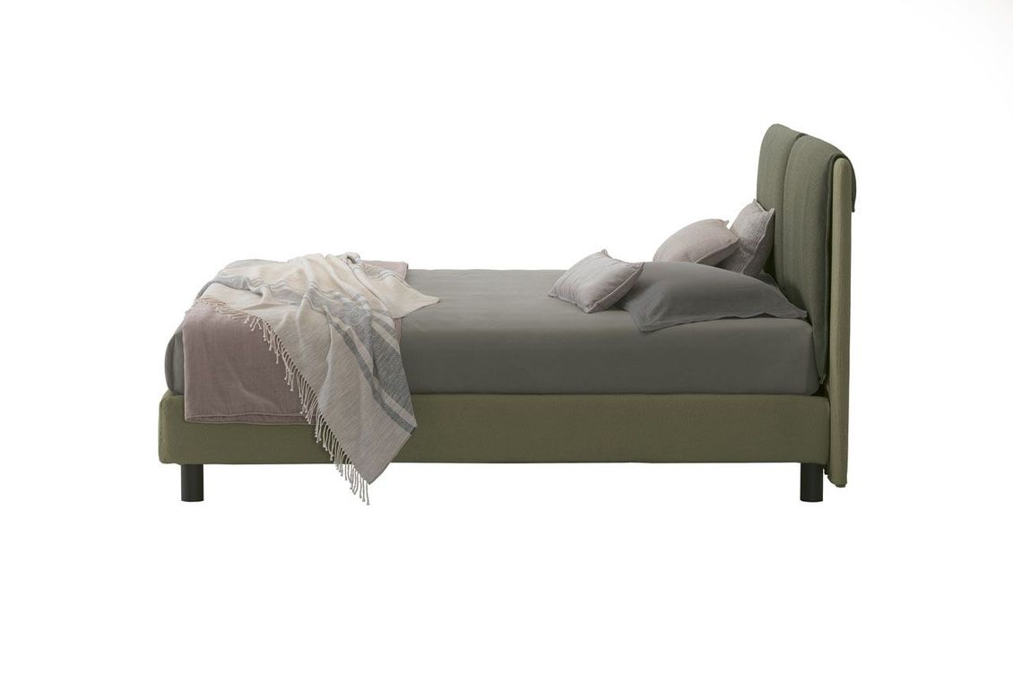 Un letto con una coperta e dei cuscini su uno sfondo bianco.