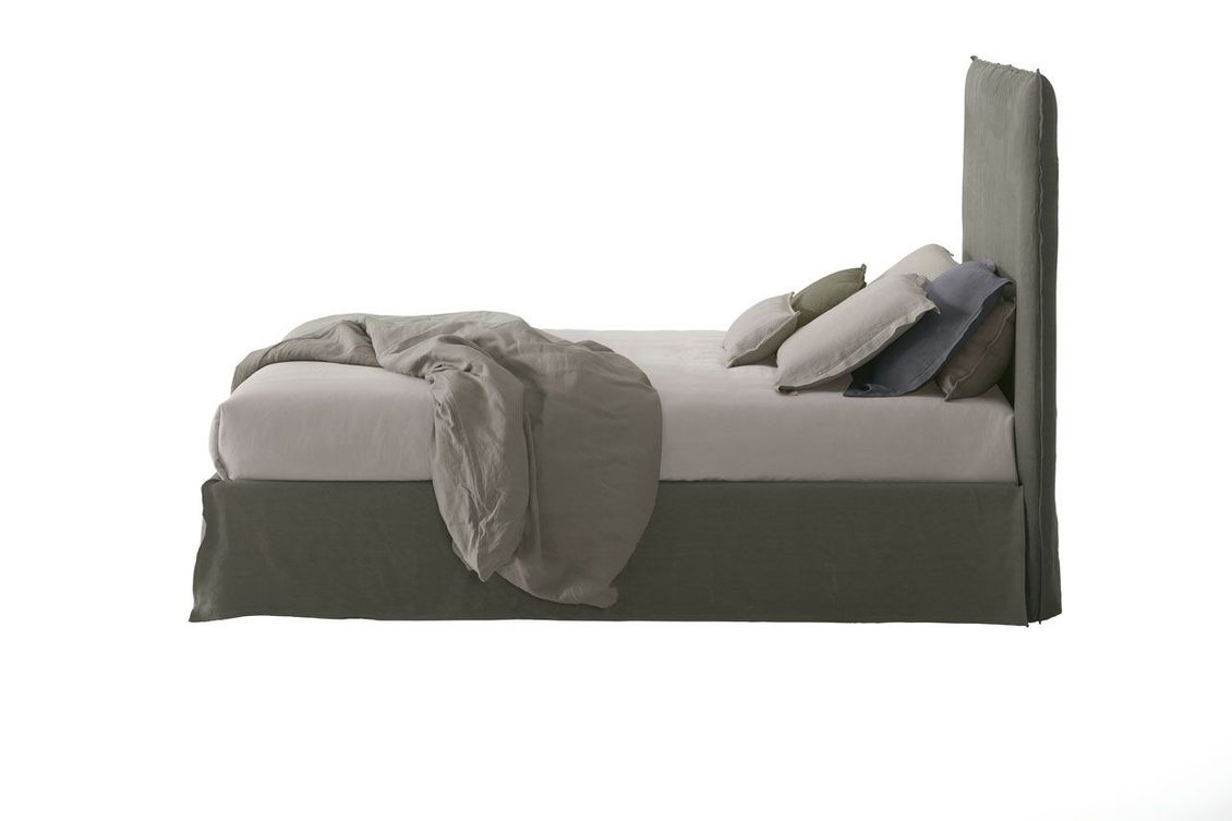 Un letto con una coperta e dei cuscini su uno sfondo bianco.