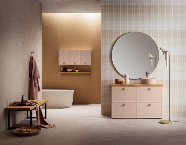 Un bagno con mobili rosa e uno specchio rotondo