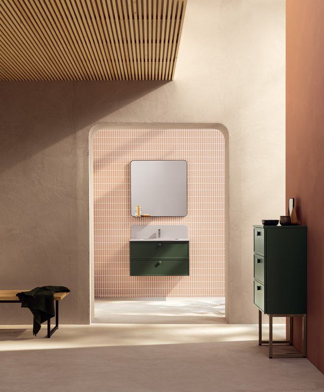 Un bagno con un mobiletto verde e uno specchio